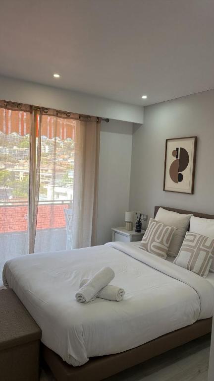a bedroom with a large white bed with a window at Appartement Valeria in Saint-Laurent-du-Var