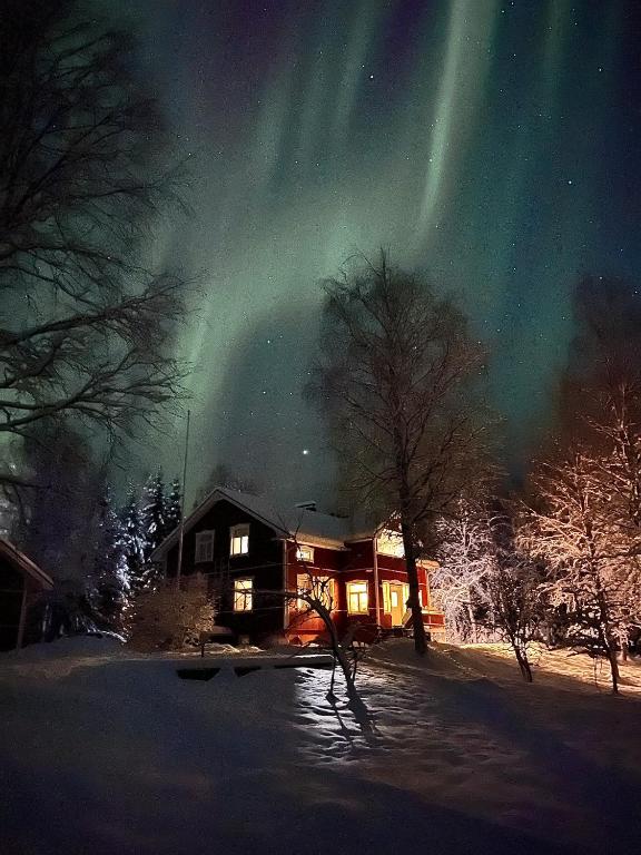 a house under the northern lights in the sky at Lapland Dream Destinations in Rovaniemi