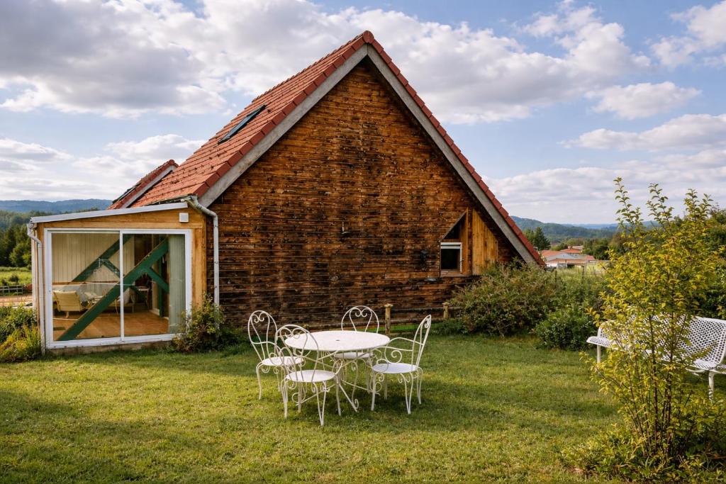 a barn with a table and chairs in the yard at Chalet avec jardin et vue 6 personnes in Espezel