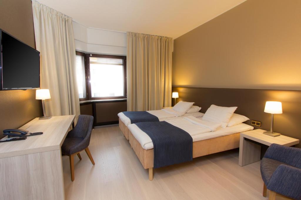 um quarto de hotel com uma cama grande e uma secretária em Hotel Oscar em Varkaus