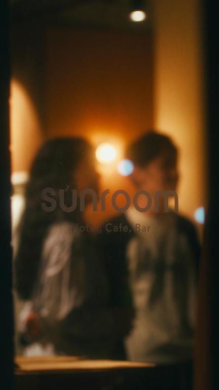 two people standing in a room with a sunoco sign at sunroom Hotel,Cafe,Bar in Miyazaki