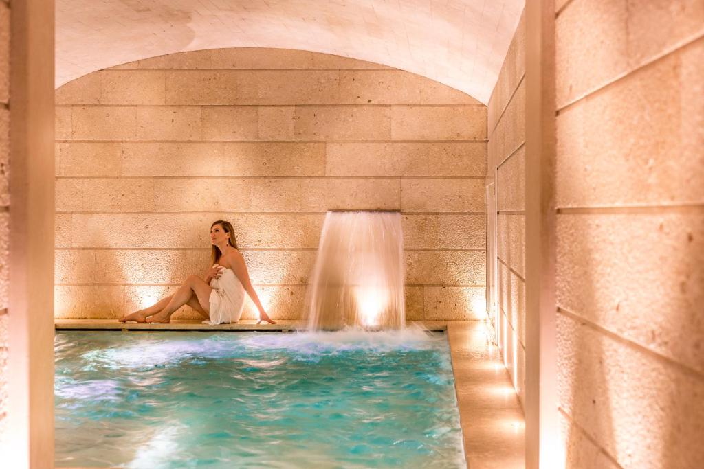 
a woman standing in a bath tub next to a pool at Palazzo Gattini Luxury Hotel in Matera
