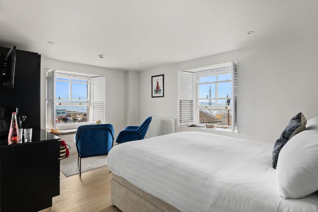a bedroom with a white bed and two blue chairs at Pilgrim Suite - Sea View - Free Wi-Fi in Brixham