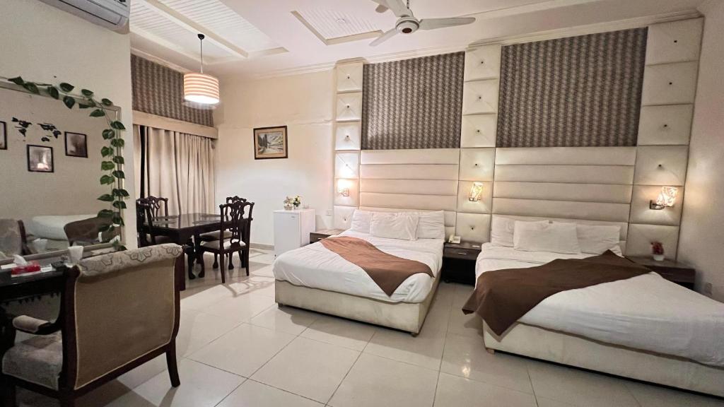 a bedroom with two beds and a desk and a dining room at Adams Lodge F-7 in Islamabad