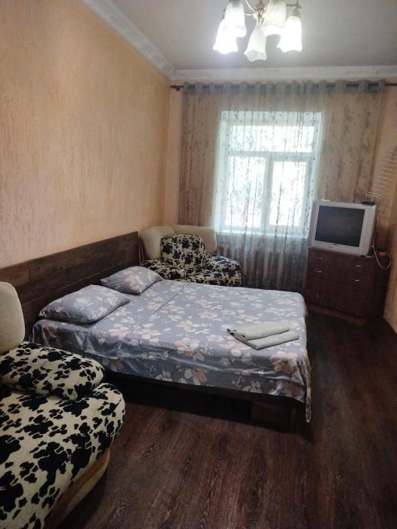 a small bedroom with two beds and a tv at Letto UTZ in Mykolaiv