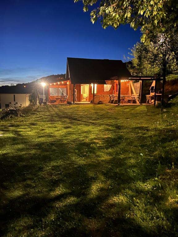 a log cabin with a lit up yard at night at Log cabin in Sejdanovići