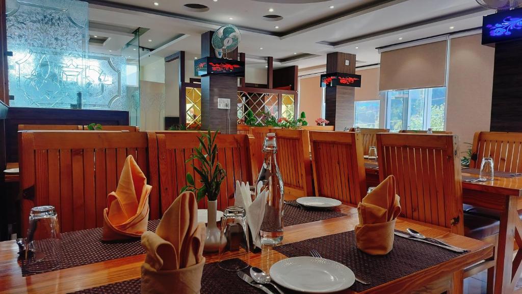 ein Restaurant mit einem Holztisch, Tellern und Servietten in der Unterkunft Hotel Nature's View in Dharamshala