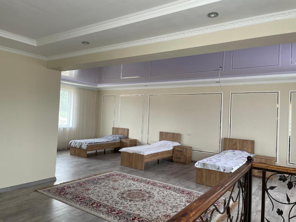 a large room with two beds and a rug at Zhailoo Guest House Kochkor in Kochkorka