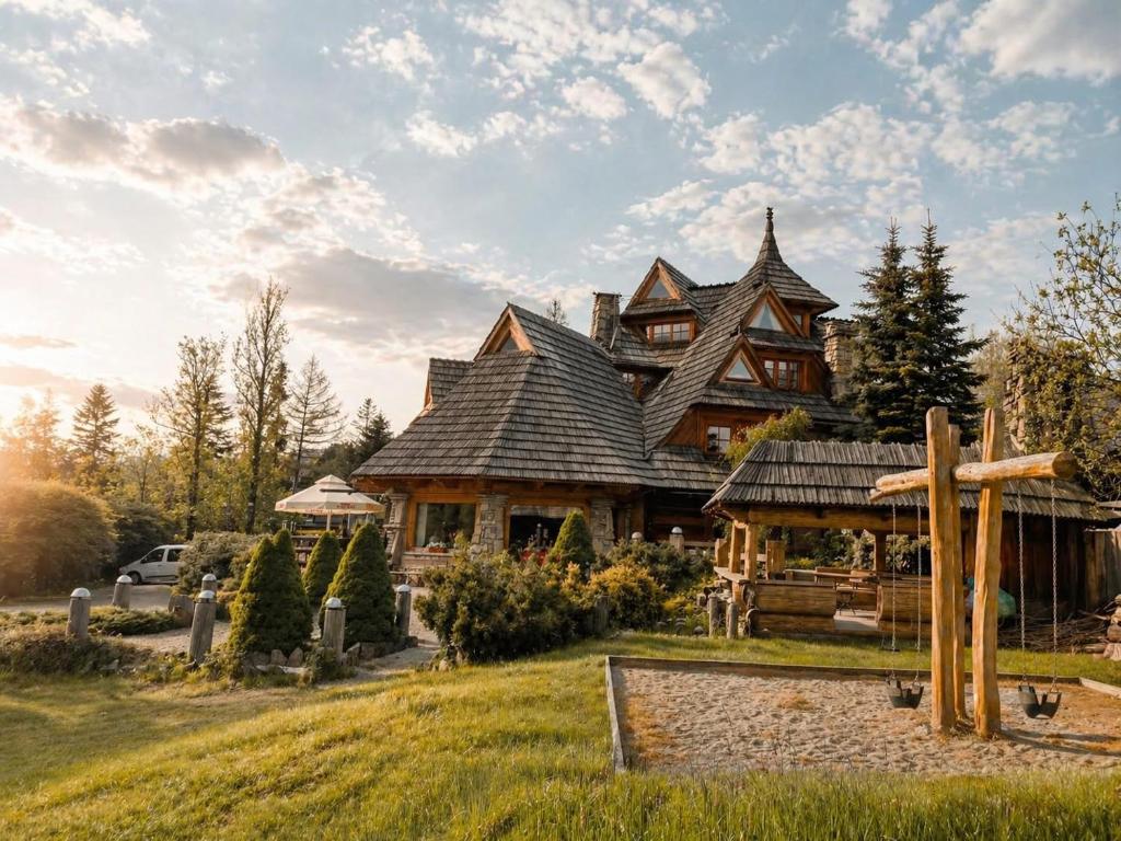 a large wooden house with a cross in front of it at Góralski Dwór in Kościelisko
