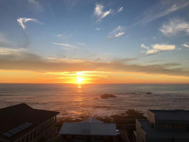 a sunset over the ocean with the sun setting at Emmaus-On-Sea in Yzerfontein