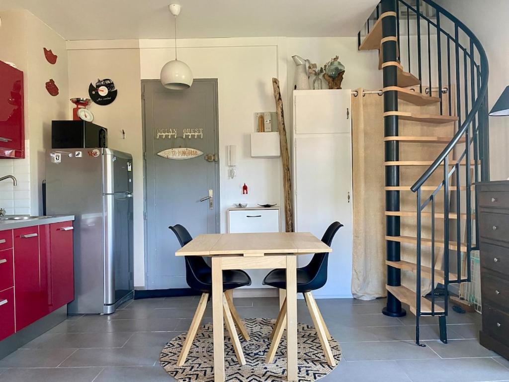 eine Küche mit einem Holztisch und einer Treppe in der Unterkunft Duplex studio Moulleau proche plage avec chambre en mezzanine in Arcachon