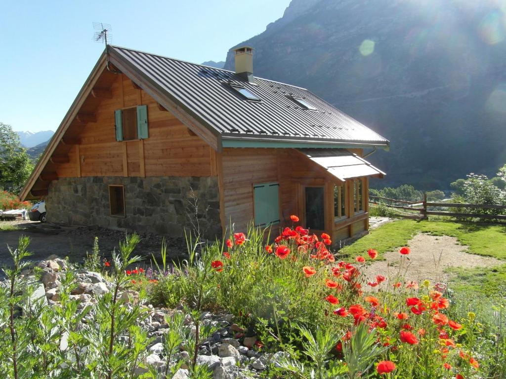 a log cabin with flowers in front of it at gîte l'écureuil roux in LʼArgentière-la-Bessée
