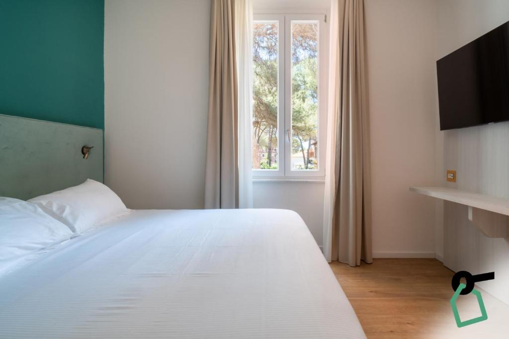 a bedroom with a white bed and a window at Hotiday Castiglioncello Suite in Castiglioncello