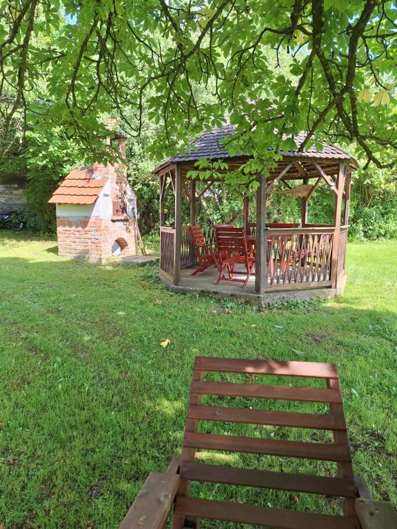 a wooden gazebo with a bench in the grass at Gergócs Vendégház in Őriszentpéter