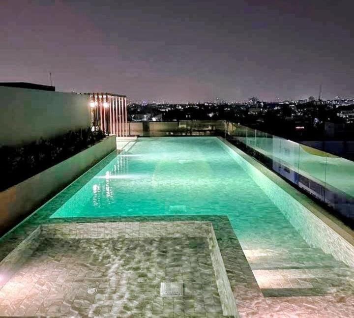 a swimming pool on top of a building at night at Bangkok Esque Sukhumvit101 Condo NEW Building in Amphoe Phra Khanong