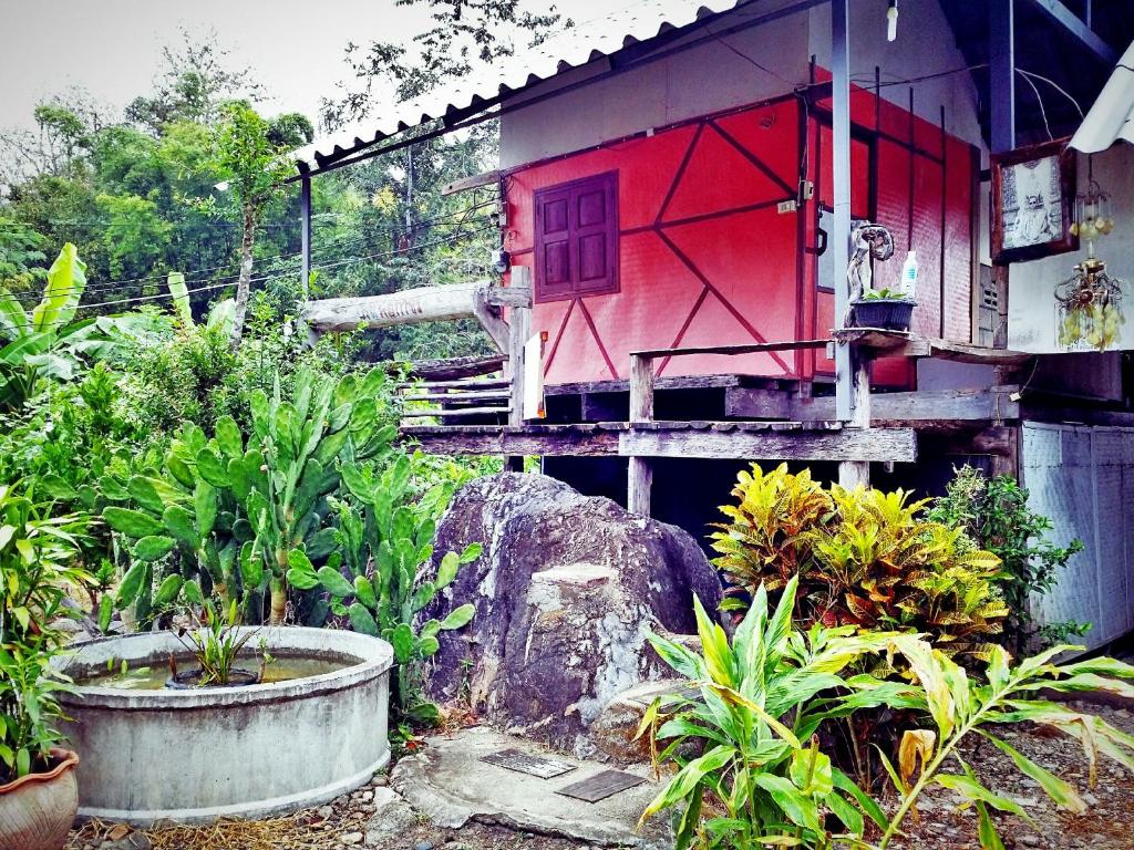 une maison avec une porte rouge dans un jardin dans l'établissement Baan Pai Likit, à Pai