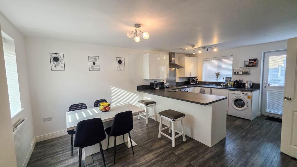 a kitchen with a table and some chairs in a room at Spacious and Modern 4BR with Hot Tub and Garden in Peterborough