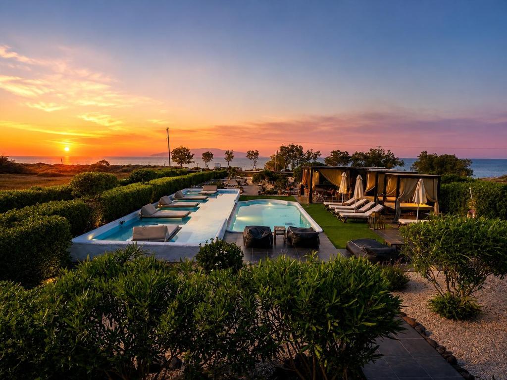 a resort with a swimming pool and a sunset at Mare Nostrum Santo in Oia