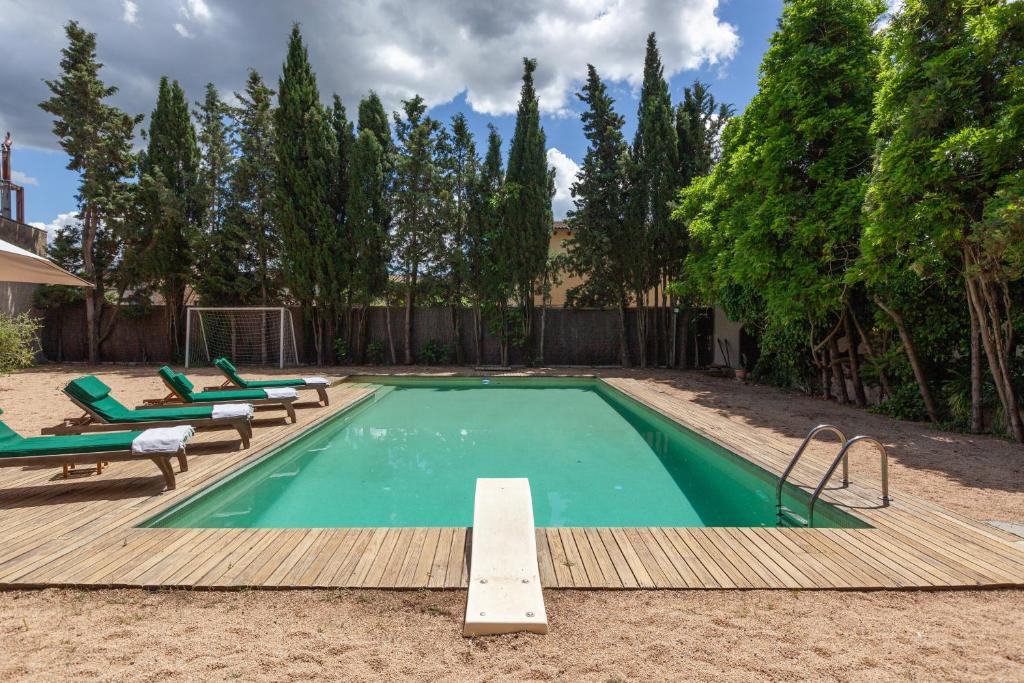 a small swimming pool with green chairs and a wooden deck at Masia del siglo xvi in Vallbona