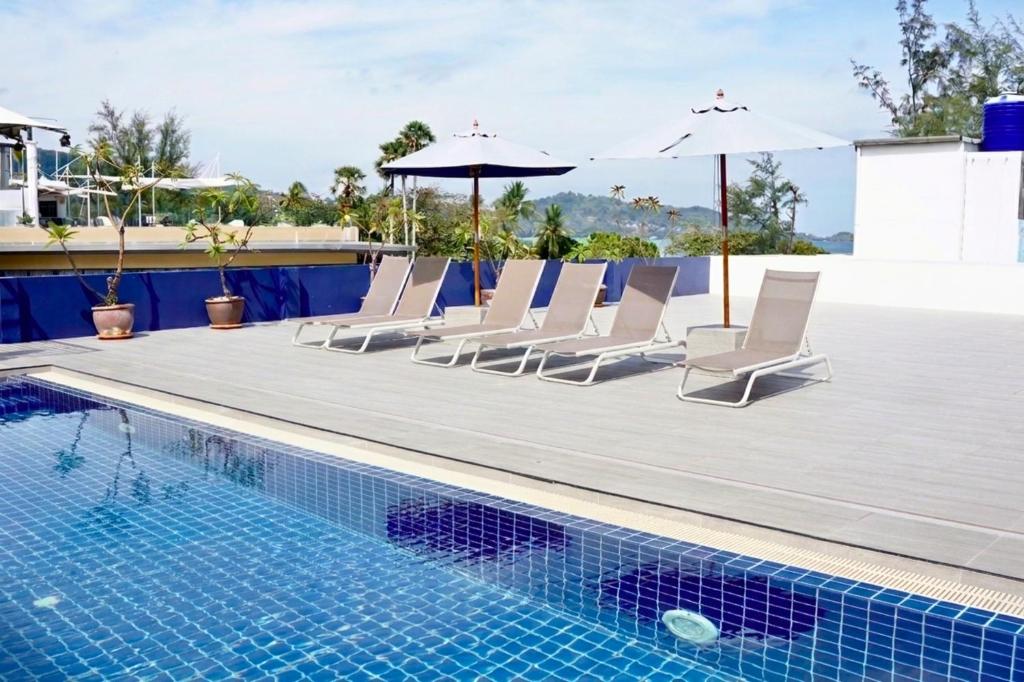 a pool with lounge chairs and umbrellas next to a swimming pool at Kokotel Phuket Patong in Patong Beach