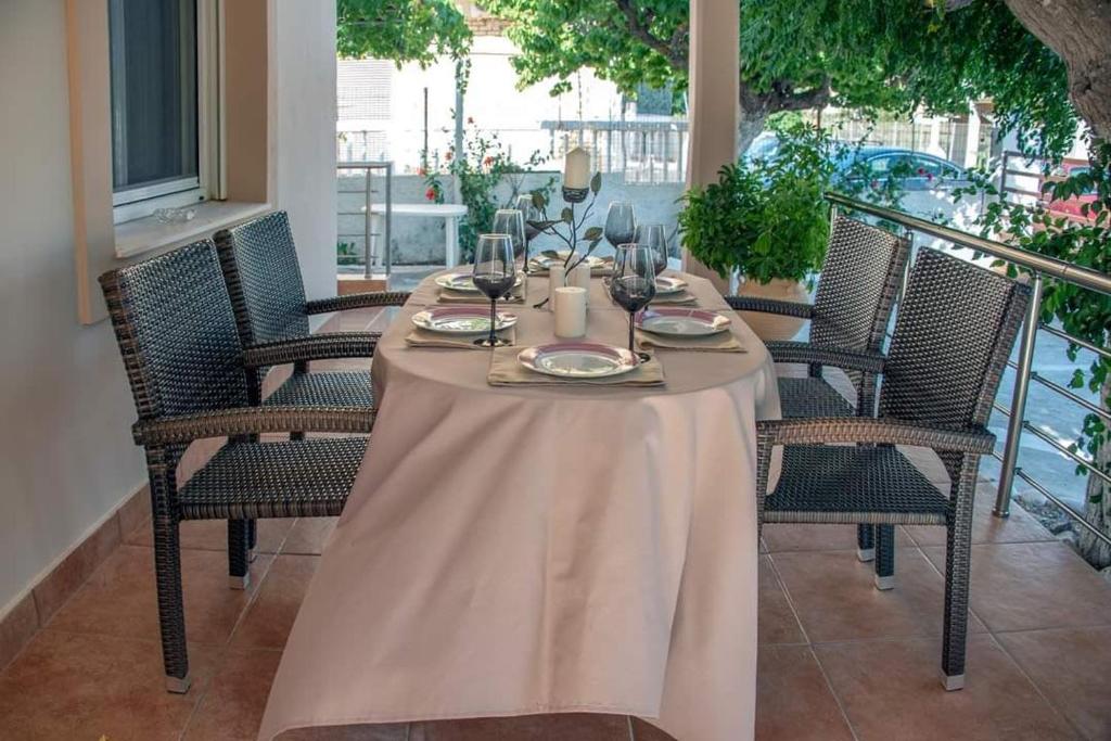 a table with wine glasses on a balcony at Seaside Plitra Paradiso - Steps from the Beach in Plytra