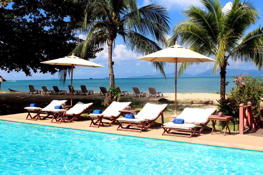 a pool with chairs and umbrellas next to the beach at The Waterfront Hotel at Fishermans Village in Bophut 