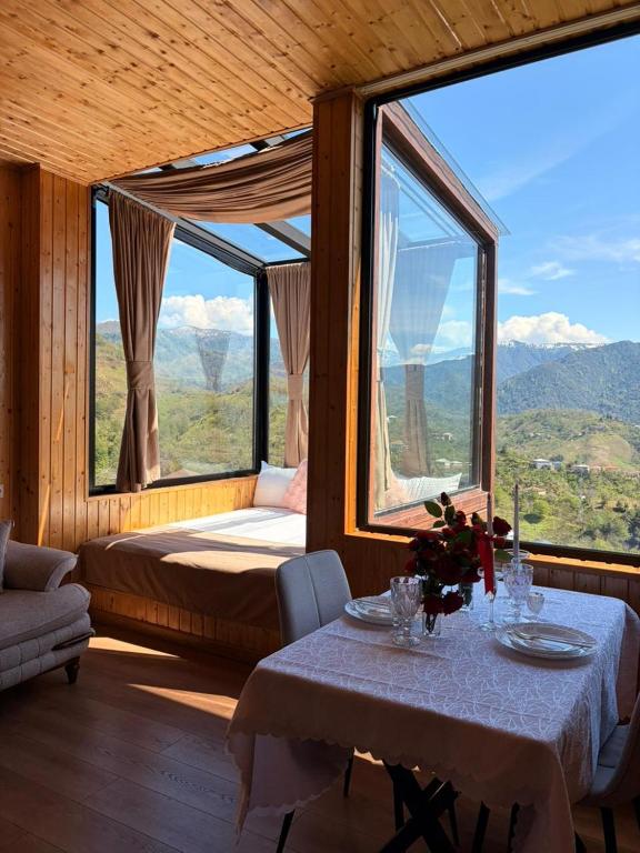a room with a table and a bed and large windows at Villa Kapreshumi in Itʼkhvisi