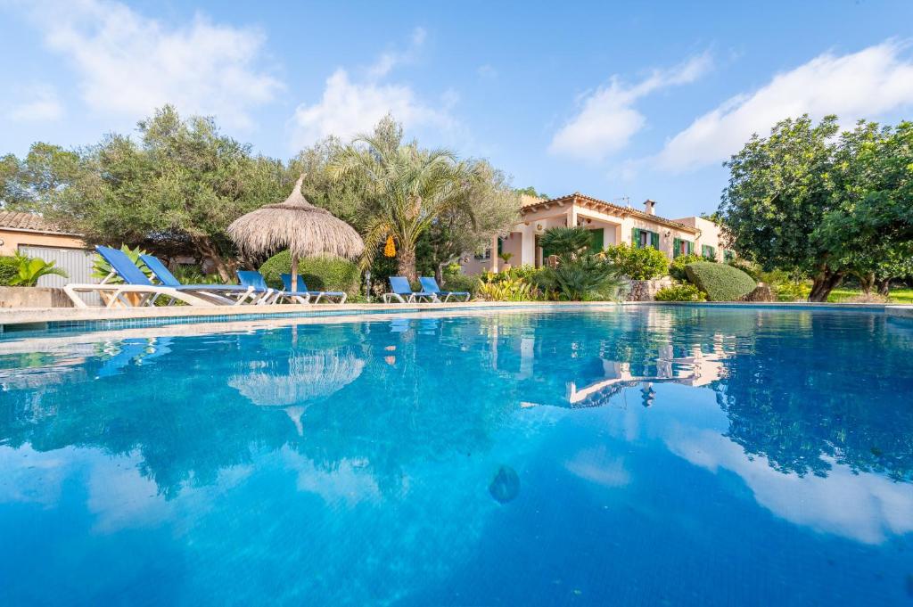 a swimming pool with blue chairs and a house at Finca Binifarda by Mallorca House Rent in Felanitx