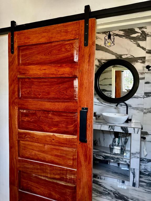a wooden door in a bathroom with a mirror at The Cozy Cottage in Ndola