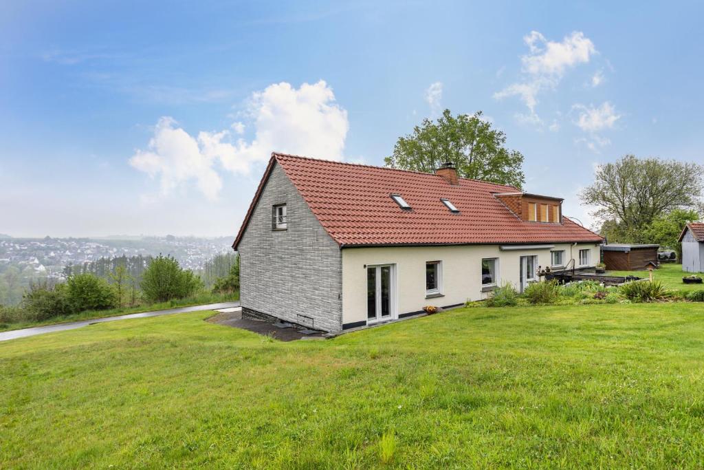a house with a red roof on a green field at Ferienwohnung Gerke in Warstein