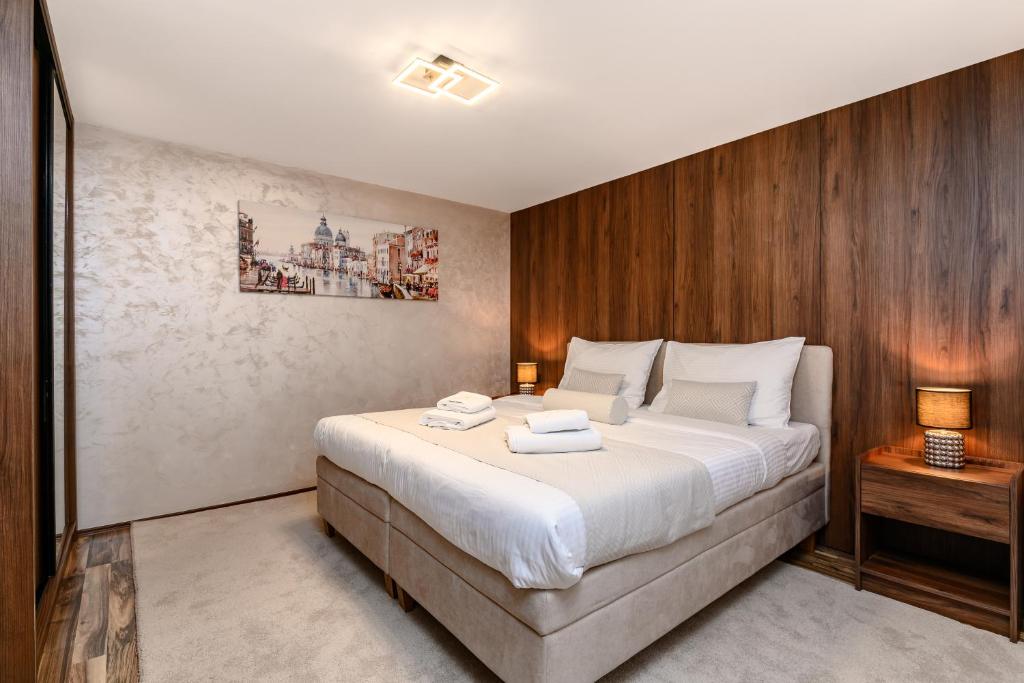 a bedroom with a large bed and a wooden wall at One Luxury Suites AKUSTIK - 3 minuta peške do Jezera in Zlatibor