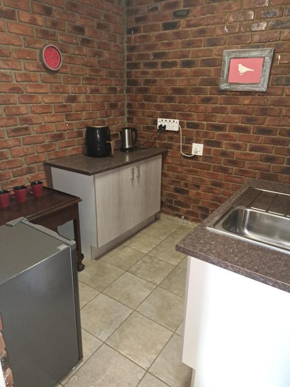 a kitchen with a sink and a brick wall at Siësta Guesthouse in Modimolle
