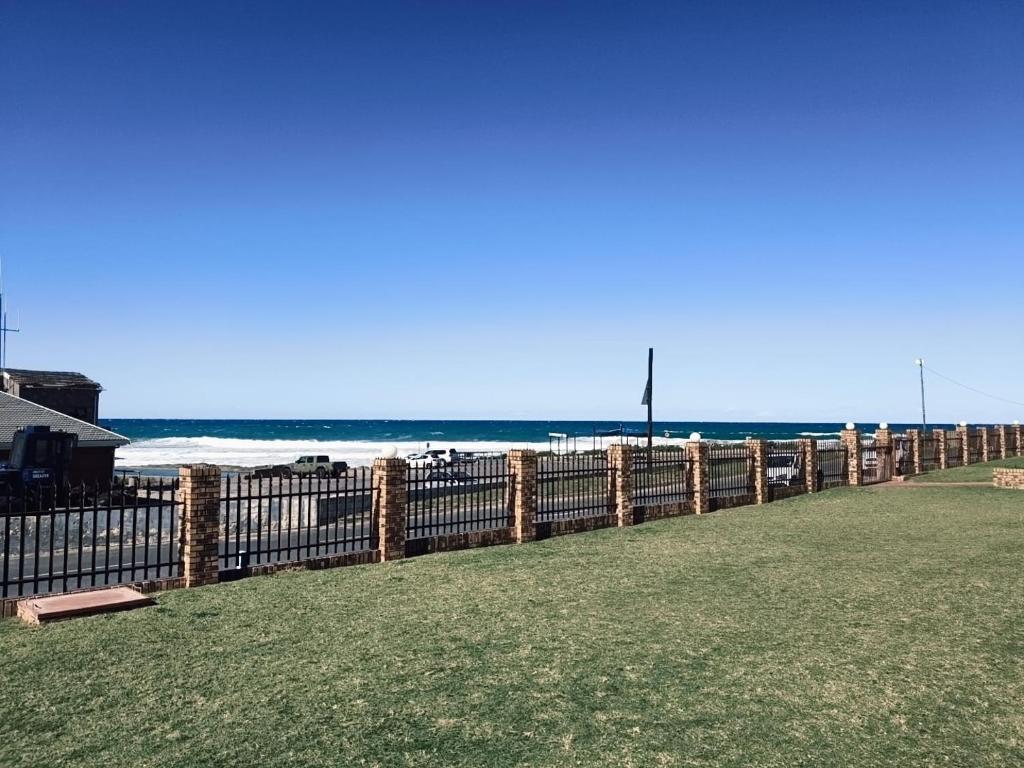 a fence next to a beach with the ocean at Eden Dunes 75B in Shelly Beach