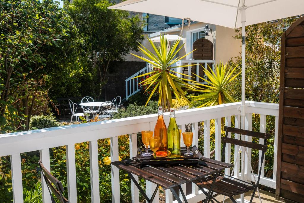 a table with drinks and an umbrella on a porch at Gîte L'inattendue in Courseulles-sur-Mer