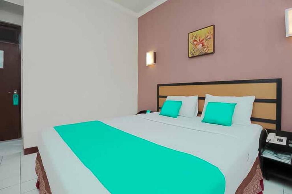 a bedroom with a large bed with green pillows at Hotel Lestari Near Lippo Plaza Mall Jember in Jember