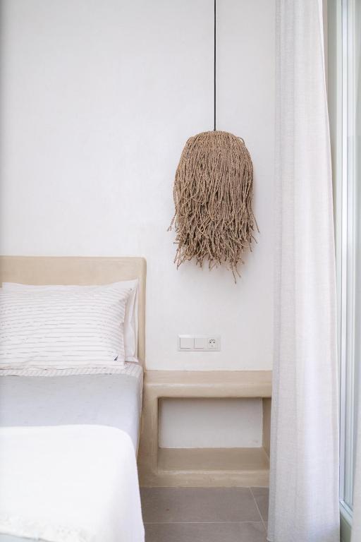 a white bedroom with a bed and a chandelier at Small Cyclades Houses in Koufonisia