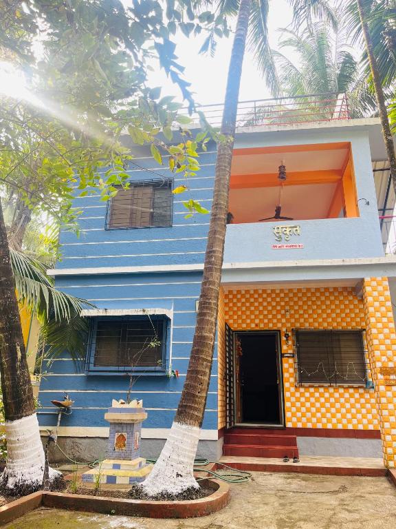 a blue house with palm trees in front of it at Sukrut Villa, Alibag in Thāl