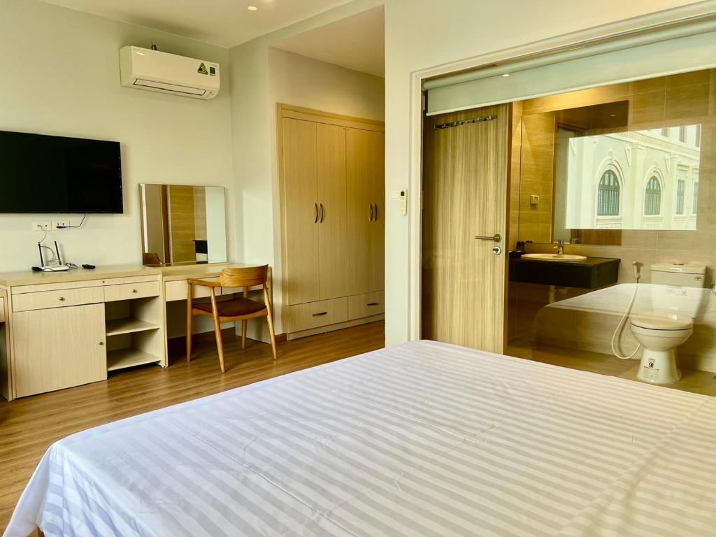 a bedroom with a white bed and a bathroom at Emerald Marina TL in Phú Quốc