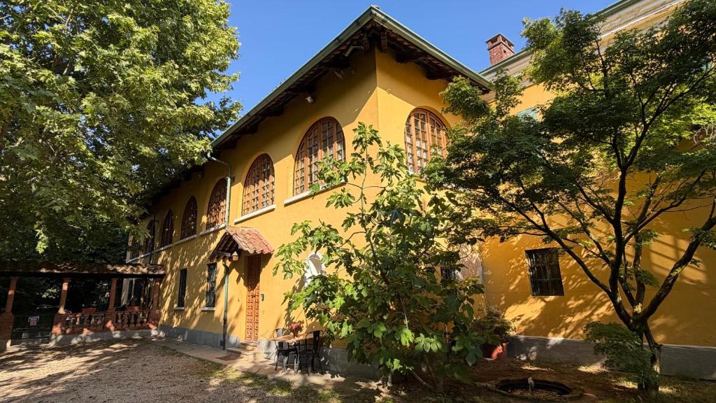 a yellow building with a tree in front of it at Cascinotto Stella Silvia in Piossasco
