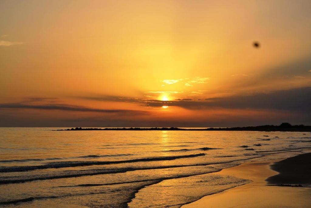 a sunset on the beach with the ocean at Giostemar Rooms - Playa Grande in Scicli