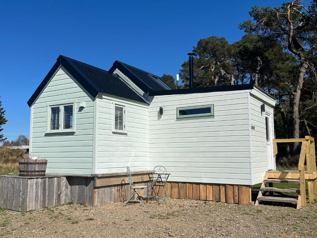 a small white house with a black roof at Corriemuckloch Unique Huts in Dunkeld