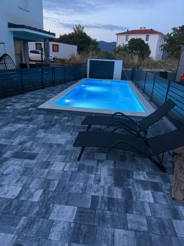 a swimming pool with a chair next to it at Apartman sa pogledom na more- Petra in Šilo