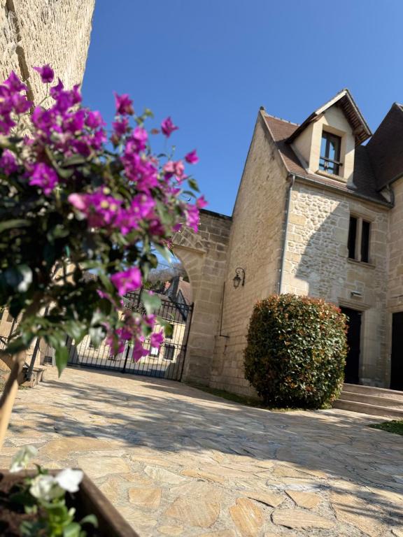 a building with a gate with pink flowers in front of it at Le Château des saveurs in Mello