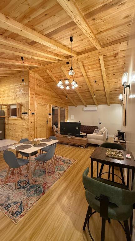 a living room with wooden ceilings and a table and chairs at كوخ الجنة in Abha