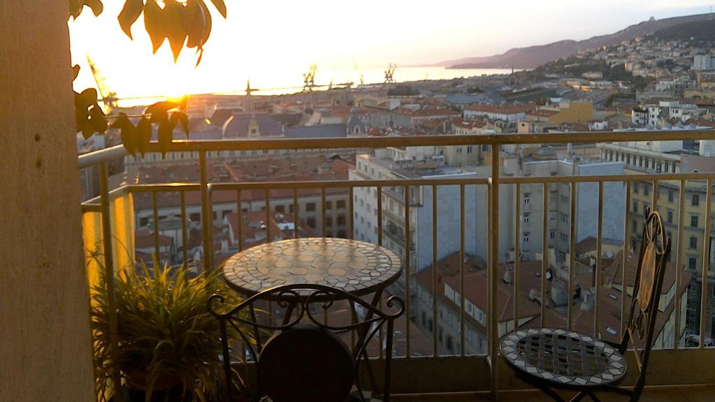 una mesa y sillas en un balcón con vistas a la puesta de sol en La Finestra Sul Mare, en Trieste
