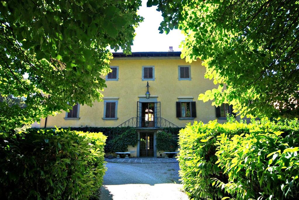 ein großes gelbes Haus hinter einigen Bäumen in der Unterkunft Villa Salaiole in Castiglione