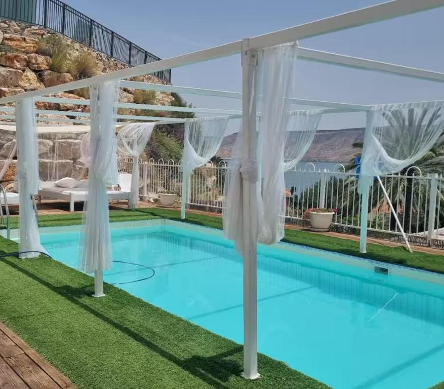 a swimming pool with a pergola and a swimming poolvisor at אצל דניאל במושבה - 2 צימרים מושלמים עם נוף לכינרת in Kinneret