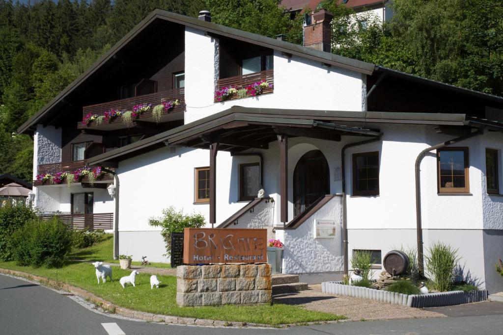 ein weißes Gebäude mit einem Schild davor in der Unterkunft Hotel Restaurant Brigitte in Warmensteinach