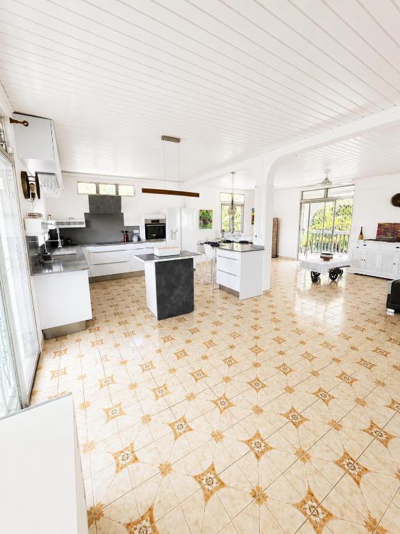 a large kitchen with white cabinets and a tile floor at La Mansarde in Le Robert