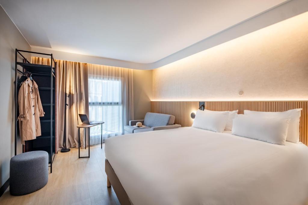 a hotel room with a large white bed and a chair at Novotel Marseille Centre Gare in Marseille